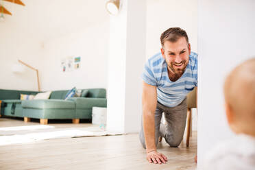 Handsome young father with a baby son at home, crawling on the floor. - HPIF30300