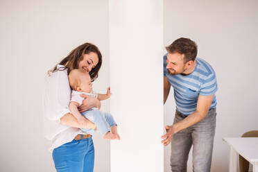 Young family with a baby boy at home, having fun. Father, mother with a son playing hide and seek. - HPIF30303