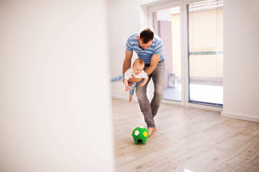 Handsome young father with a baby son at home, playing with a ball. - HPIF30311