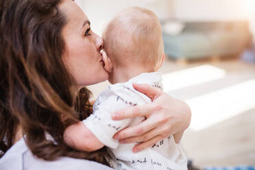 Porträt einer attraktiven jungen Mutter, die ihren kleinen Sohn zu Hause küsst, Nahaufnahme, Raum kopieren. - HPIF30313