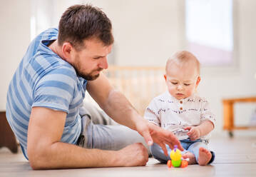 Handsome young father playing with a baby son at home. - HPIF30320