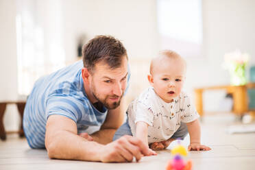 Hübscher junger Vater, der mit seinem kleinen Sohn zu Hause spielt. - HPIF30321