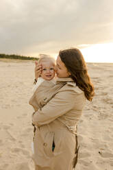 Frau umarmt und trägt Sohn am Strand - VIVF00955