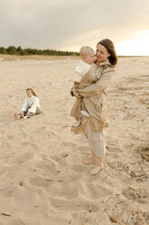 Glückliche Frau mit Sohn am Strand stehend - VIVF00956