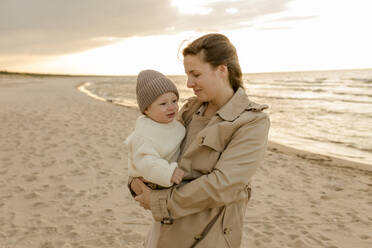 Smiling woman standing with son at beach - VIVF00958