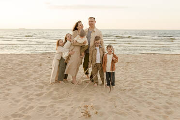 Glückliche Familie steht vor dem Meer am Strand - VIVF00993