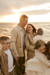 Glückliche Familie, die sich bei Sonnenuntergang an der Küste amüsiert - VIVF01001