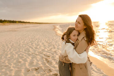 Lächelnde Frau, die ihre Tochter am Strand umarmt - VIVF01012