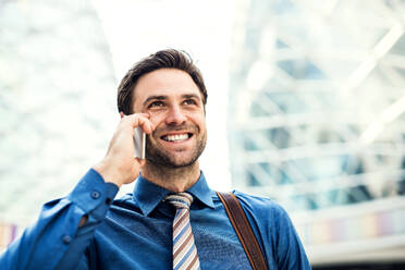 A young handsome businessman with smartphone, making a phone call. Copy space. - HPIF30351