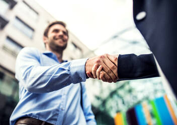 A young businessman and unrecognizable businesswoman shaking hands. A close up. - HPIF30392