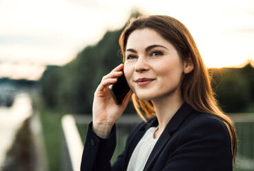 Eine Nahaufnahme einer jungen Geschäftsfrau mit Smartphone im Freien, die einen Anruf tätigt. - HPIF30422