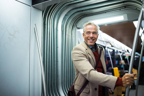 Reifer, gut aussehender Geschäftsmann mit Smartphone, der mit der Straßenbahn in der Stadt Prag unterwegs ist. - HPIF30452