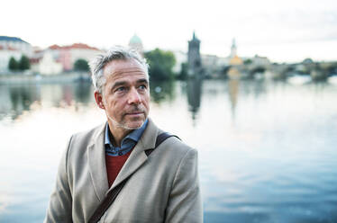 Reifer, gut aussehender Geschäftsmann, der am Fluss Moldau in der Stadt Prag steht, Kopierraum. - HPIF30470