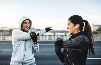Ein fittes, sportliches Läuferpaar macht Dehnübungen im Freien auf einer Brücke in Prag, Tschechische Republik. - HPIF30510