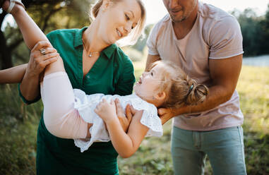 Junge Familie mit einer kleinen Tochter, die gemeinsam Zeit in der sonnigen Sommernatur verbringen und Spaß haben. - HPIF30572