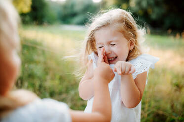 Two small girl friends or sister playing outdoors in sunny summer nature, having fun. - HPIF30585