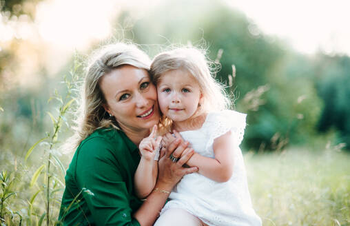 Porträt einer jungen Mutter in der Natur mit ihrer kleinen Tochter im Sommer, Vorderansicht. - HPIF30588