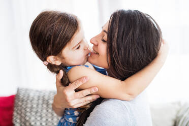 Junge Mutter mit einem kleinen Mädchen zu Hause, die sich umarmen. - HPIF30600
