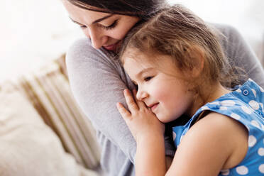 Young mother with a small girl at home, hugging. - HPIF30601