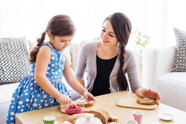 Young mother with a small girl at home, eating. - HPIF30606