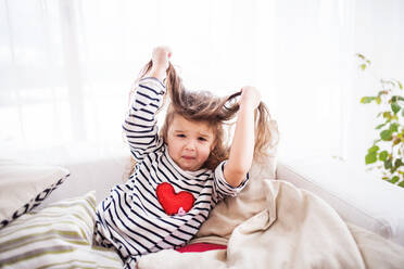 Ein süßes kleines Mädchen im gestreiften T-Shirt, das sich zu Hause amüsiert. - HPIF30630