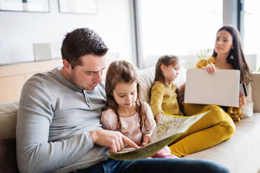 Porträt einer jungen, glücklichen Familie mit zwei Kindern, die sich zu Hause auf die Ferien vorbereiten. - HPIF30661