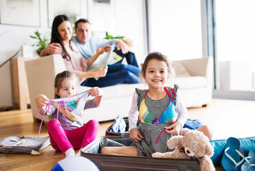 Porträt einer jungen, glücklichen Familie mit zwei Kindern beim Packen für den Urlaub zu Hause. - HPIF30668