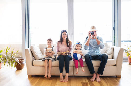 Porträt einer jungen glücklichen Familie mit zwei Kindern, die sich zu Hause auf den Urlaub vorbereiten. - HPIF30671
