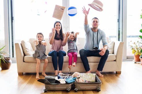 Porträt einer jungen, glücklichen Familie mit zwei Kindern beim Packen für den Urlaub zu Hause. - HPIF30673