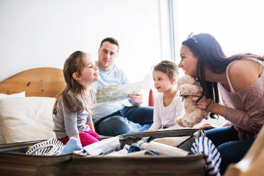 Porträt einer jungen, glücklichen Familie mit zwei Kindern beim Packen für den Urlaub zu Hause. - HPIF30675