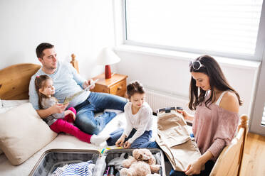 Porträt einer jungen, glücklichen Familie mit zwei Kindern beim Packen für den Urlaub zu Hause. - HPIF30676