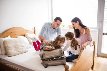 Porträt einer jungen, glücklichen Familie mit zwei Kindern beim Packen für den Urlaub zu Hause. - HPIF30678
