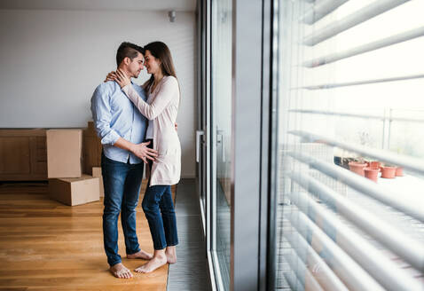 Young happy couple with cardboard boxes moving in a new home, hugging. Copy space. - HPIF30690