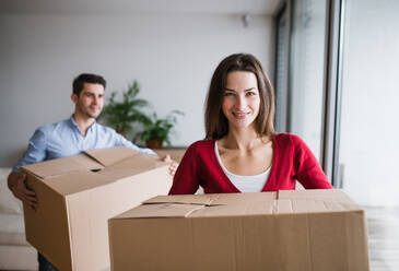 Ein junges, glückliches Paar zieht in ein neues Haus und hält Kartons in der Hand. - HPIF30710