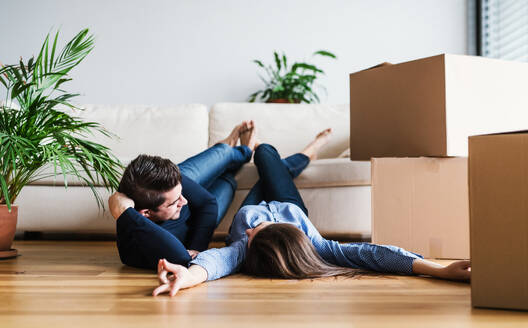 A young couple with cardboard boxes lying on the floor, moving in a new home. - HPIF30717