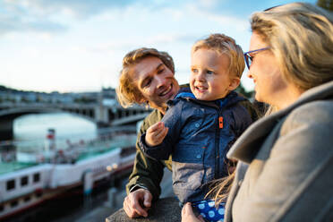 Young parents with their toddler son standing outdoors by the river in city of Prague. - HPIF30822