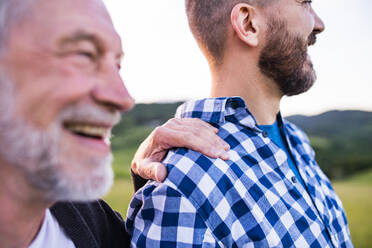 An adult hipster son with his senior father on a walk in nature at sunset. Close up. - HPIF30950