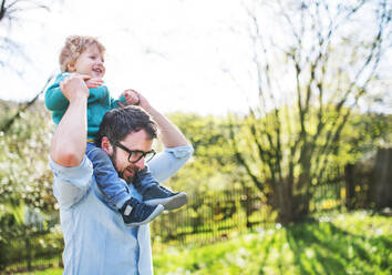 A father with his toddler son outside in green sunny spring nature, having fun. Copy space. - HPIF30960