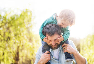 A father with his toddler son outside in green sunny spring nature, having fun. - HPIF30961