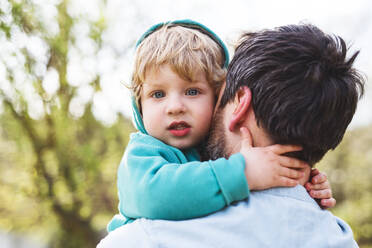 An unrecognizable father with his toddler son outside in green sunny spring nature, having fun. - HPIF30963