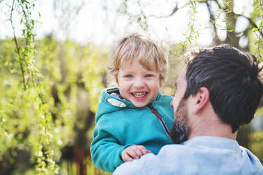 An unrecognizable father with his toddler son outside in green sunny spring nature, having fun. - HPIF30964