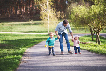 A father with his two toddler children outside on a sunny spring walk. - HPIF30973