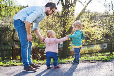 A father with his two toddler children outside on a sunny spring walk. - HPIF30976