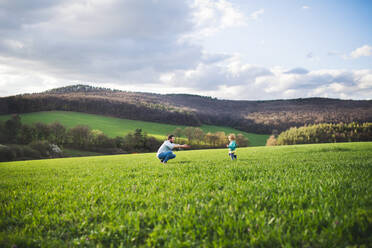 A mature father with his toddler son running outside in green sunny spring nature. - HPIF30983