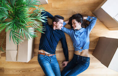 A top view of young couple with cardboard boxes lying on the floor, moving in a new home. - HPIF31029