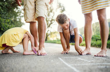 A midsection of young family with small children standing barefoot on a road in summer in countryside. - HPIF31051