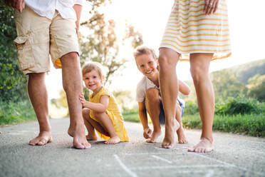 A midsection of young family with small children standing barefoot on a road in summer in countryside. - HPIF31052