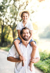 Young father in nature giving a small son a piggyback ride. - HPIF31063