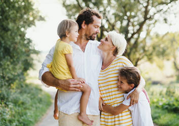 A portrait of happy young family with small children spending time together outside in green summer nature. - HPIF31065