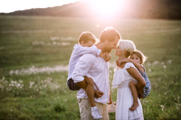 Happy young family with small children spending time together outside in green summer nature at sunset. - HPIF31087